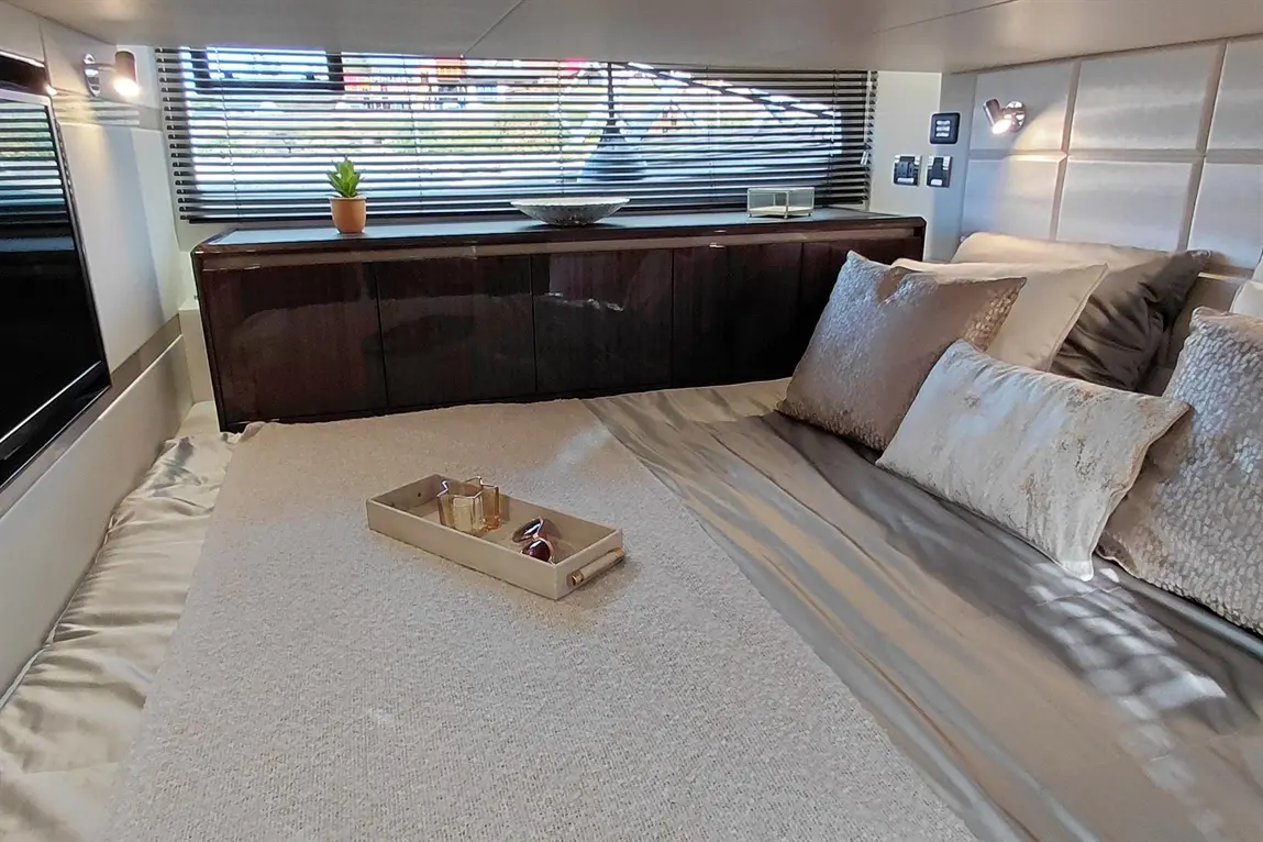 Elegant bedroom interior featuring a plush bed, decorative cushions, and ambient lighting, with a plant and storage cabinet visible.